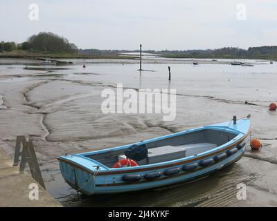 View of the mudflats and a rowing boat at low tide on the River Deben estuary at Woodbridge Tide Mill. Stock Photo