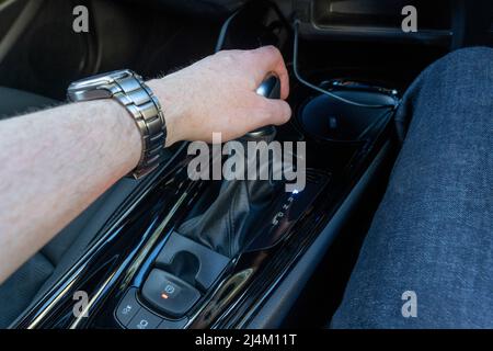 Driver's hand holding the automatic gear shift stick in a right hand drive car in the park position in a self charging petrol hybrid Toyota CH-R. UK Stock Photo