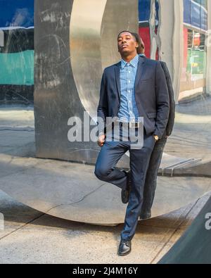 Tears in eyes, a young black businessman is leaning on a modern mirror wall, emotionally broken down. Stock Photo