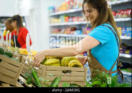 Ethnic seller putting box of bananas on counter Stock Photo