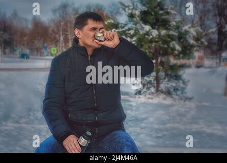 a man in a cold winter drinks coffee from a thermos and rests Stock Photo