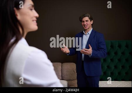 Sales rep, assistant, retail consultant explaining benefits of orthopedic mattress for healthy sleep and good posture in the expo centre of furniture Stock Photo