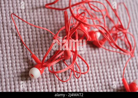 Tangled red headphones on gray background. Headphone mess Stock Photo
