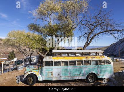 Old Obsolete Abandoned Rust Coloured School Bus Parked Under Sycamore Tree on Vehicle Junkyard Depot in Jerome, Arizona Southwest USA Stock Photo