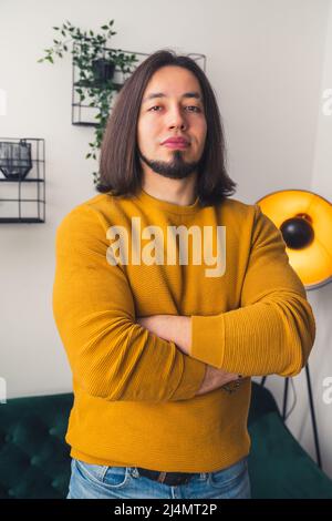 Medium shot of confident young man crossing his hands and looking at the camera casual clothes home background . High quality photo Stock Photo