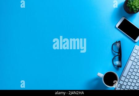 Basic work or school supplies with morning coffee on a blue desk top setting Stock Photo