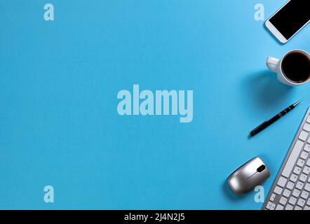 Blue office desk top with computer keyboard, cup of morning coffee and other basic supplies for work or school setting Stock Photo