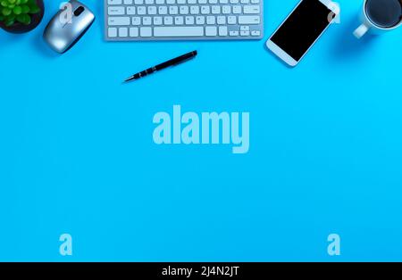 Blue office desk with computer, dark coffee and other basic supplies for work or school setting Stock Photo