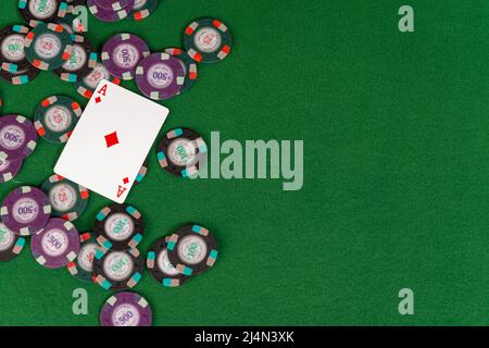 An ace of diamonds is pictured atop a pile of poker chips with copy space to the right. Stock Photo