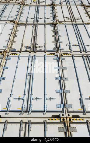 Looking up at a wall of white shipping containers from low angle Stock Photo