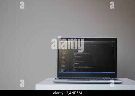 Opened laptop with code on the screen on the table Stock Photo