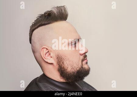 Young trendy man portrait. Punk styled man with Mohawk hairstyle on gray background Stock Photo