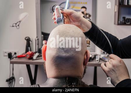 Middle aged caucasian man is cutting his own hair with an electric razor. Stock Photo