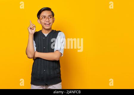 Excited handsome young man raising finger and having creative idea on yellow background Stock Photo