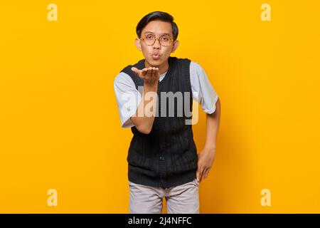 Portrait of charming young Asian man holding palms sending air kiss to girlfriend Stock Photo