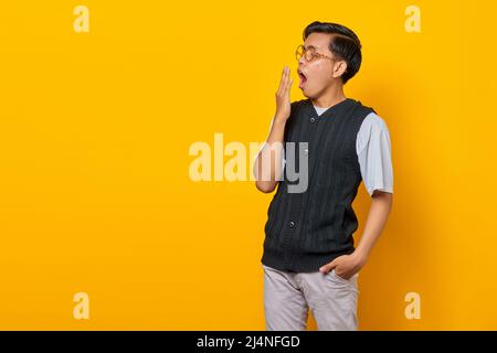 Portrait of handsome young Asian man feeling sleepy and covering mouth with hand Stock Photo