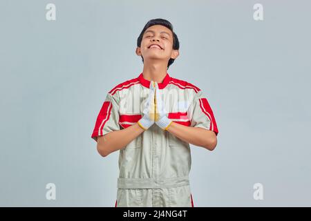 Mechanic man wearing uniform praying with hands together asking for forgiveness smiling confidently Stock Photo