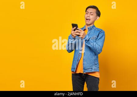 Shocked Asian young man looking at message on smartphone Stock Photo