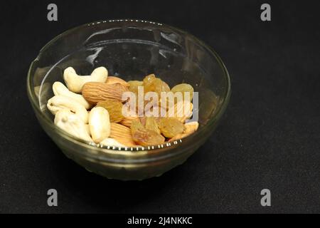 The healthy dry fruit, almond, cashews, and grapes are in a cup. On a black background Stock Photo