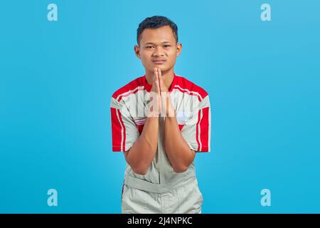 Mechanic man wearing uniform praying with hands together asking for forgiveness smiling confidently Stock Photo