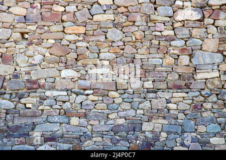 Ancient stone wall made of multicolored stones as background or backdrop Stock Photo