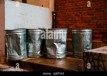 empty battered traditional american trash bins standing in a back alley in New York City Stock Photo