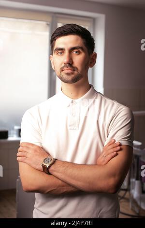 handsome young man with crossed hands near window in office Stock Photo