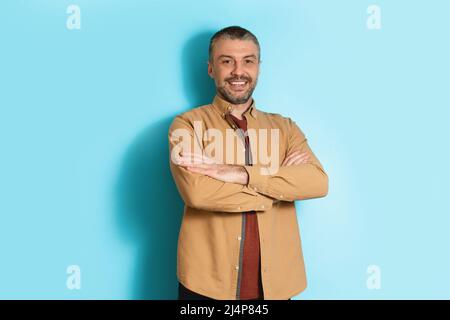 Happy Middle Aged Man Standing Crossing Hands Over Blue Background Stock Photo