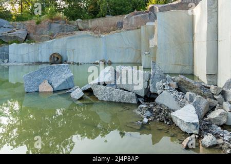 Granite quarry with large granite blocks Abandoned granite quarry with rain water. Granite mining in a quarry. Stock Photo