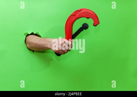 A man holds a tool for cutting plastic pipes on a green background Stock Photo