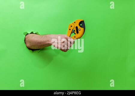 A man holds a tool for cutting plastic pipes on a green background Stock Photo