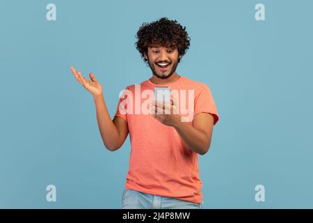 Emotional eastern guy enjoying newest mobile app Stock Photo
