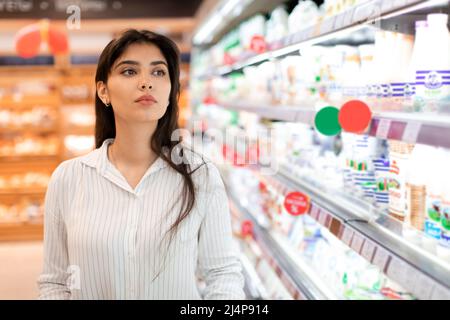 Arabic Woman Doing Grocery Shopping Standing Near Shelf In Supermarket Stock Photo