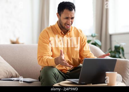 Confused Arab guy using laptop looking at screen Stock Photo
