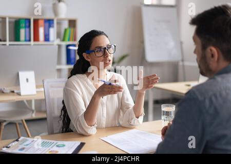 Two young colleagues communicating, discussing business project, having meeting at modern office Stock Photo