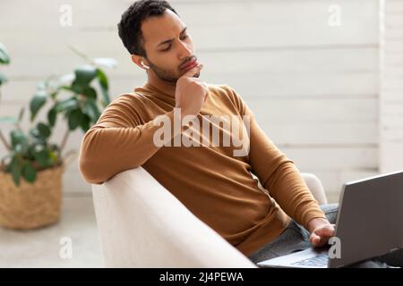 Arab man using laptop sitting on couch at home office Stock Photo