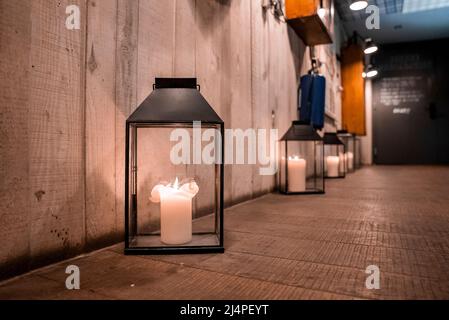 Candle lanterns arranged on floor by wooden wall at hallway in ski resort Stock Photo