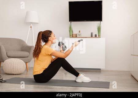 Fit Black Female Drinking Coffee Watching Television Sitting At Home Stock Photo
