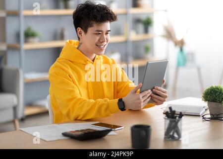 Smiling asian man using digital tablet at home Stock Photo