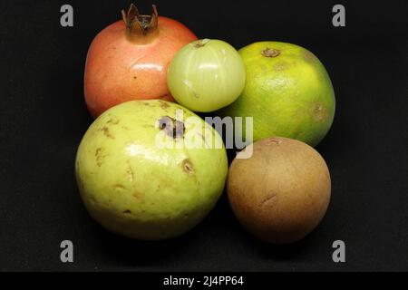 healthy fruits, sweet lime(citrus fruit) Pomegranate, Sapodilla fruit(chikku), gooseberry, on a black background Stock Photo