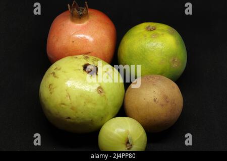 healthy fruits, sweet lime(citrus fruit) Pomegranate, Sapodilla fruit(chikku), gooseberry, on a black background Stock Photo