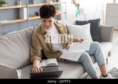 Asain man holding paper reading report working on laptop Stock Photo