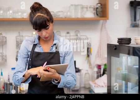 Young woman is barista using tablet computer for order delivery online in the cafe, entrepreneur and small business, employee or owner retail, commerc Stock Photo