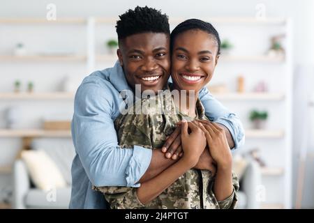 Closeup portrait of cheerful black female soldier hugging with husband Stock Photo