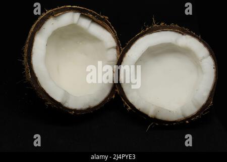coconut cut into two pieces. on a black background Stock Photo