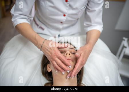 Face massage. Portrait of woman on cleaning face procedure by woman cosmetologist in beauty clinic. Beauty industry concept.  Stock Photo