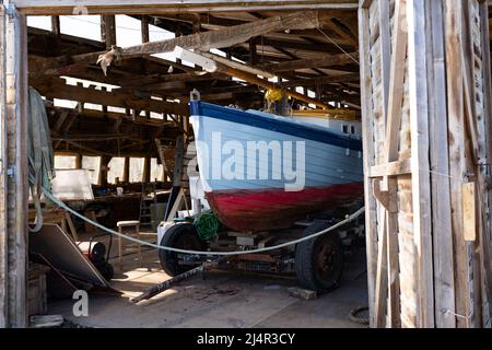 Traditional wooden sailboat in a workshop undergoing work and restoration Stock Photo