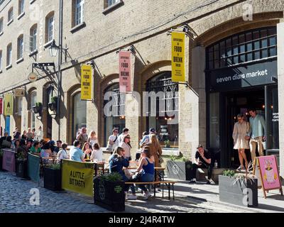 A view of people relaxing enjoying a drink on a sunny spring day at Seven Dials Market in Covent Garden London UK Stock Photo