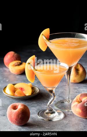 Two peach Bellinis garnished with peach slices, against a dark background. Stock Photo