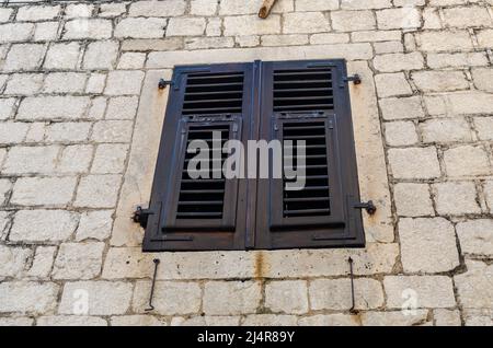 Closed window with brown shutters of an old coastal house Stock Photo